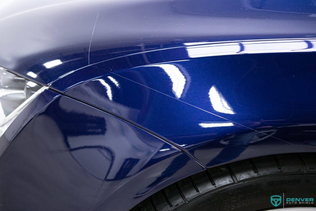 A close up of the front fender of a blue car.