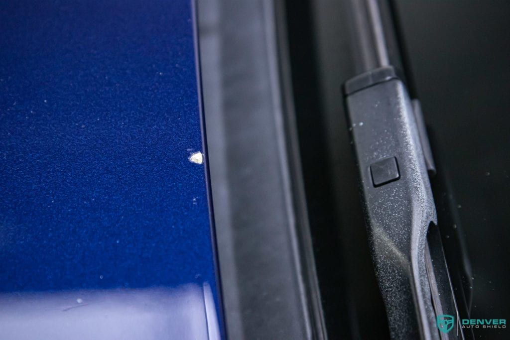 A close up of a wiper blade on a blue car.