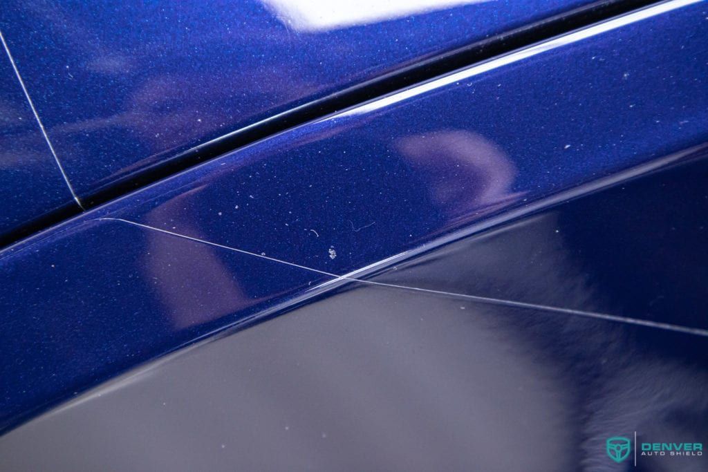 A close up of a blue car with a reflection of a person in it.