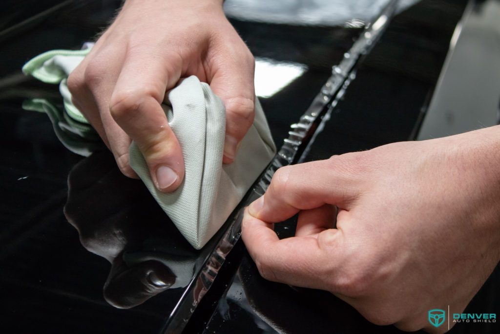 A person is cleaning a car with a cloth.