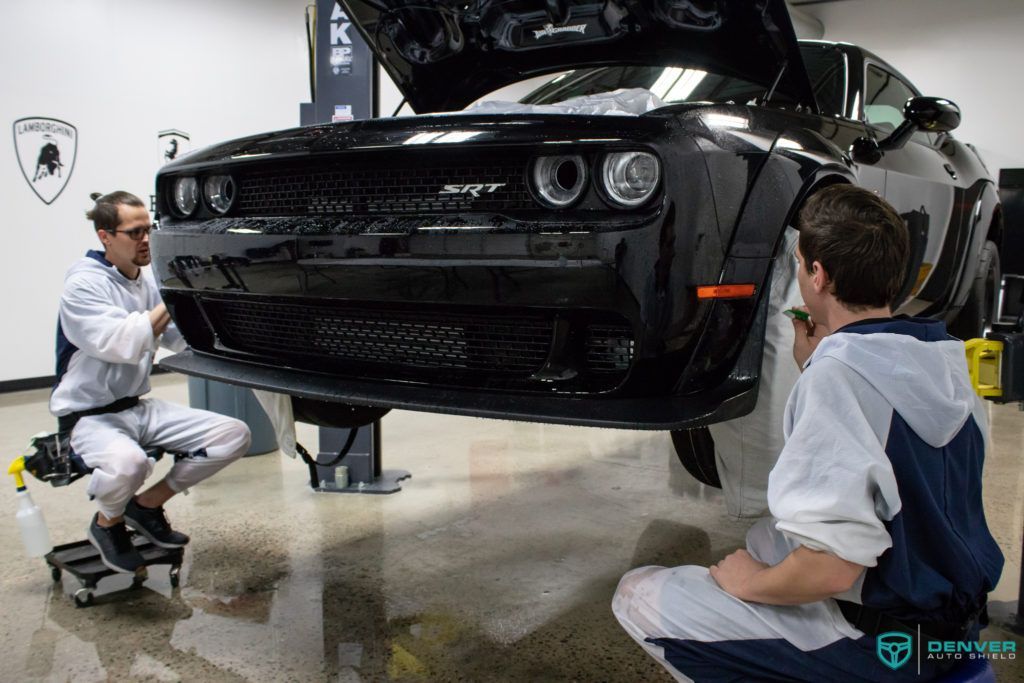 Two men are working on a dodge challenger in a garage.