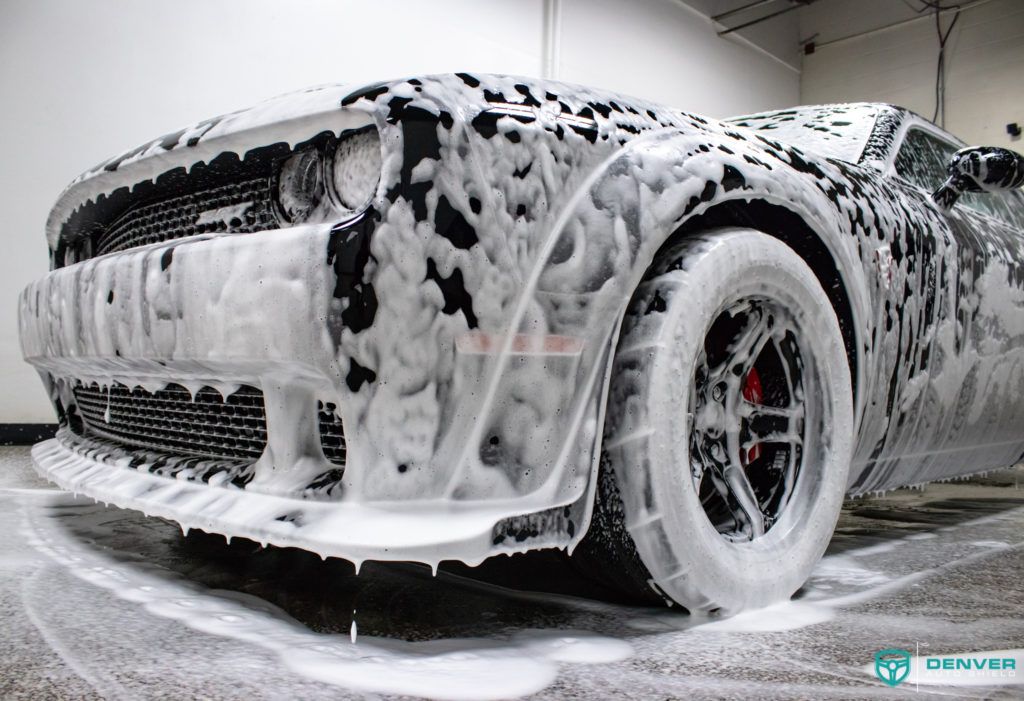 A car is covered in foam in a garage.