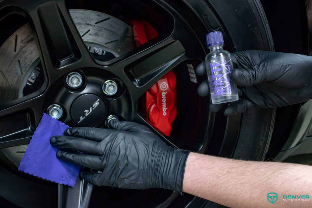 A person wearing black gloves is polishing a car wheel.