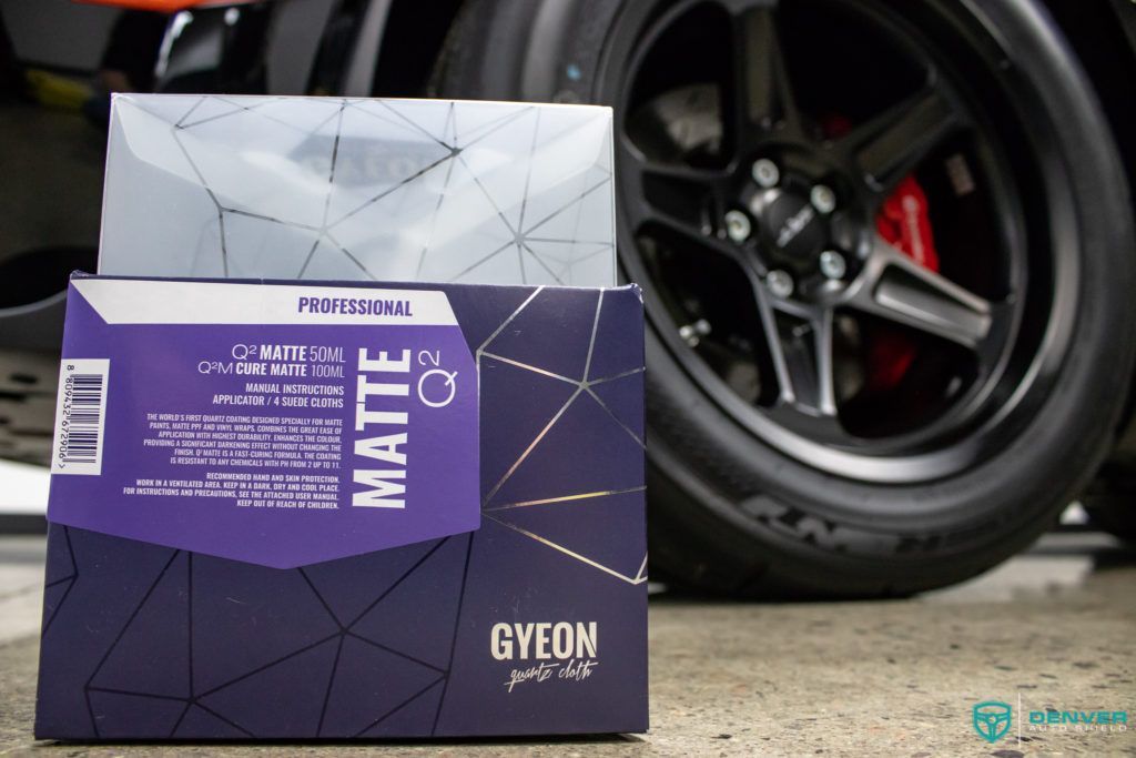 A box of gyeon matte is sitting next to a car wheel.