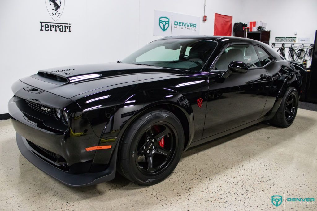 A black dodge challenger demon is parked in a garage.