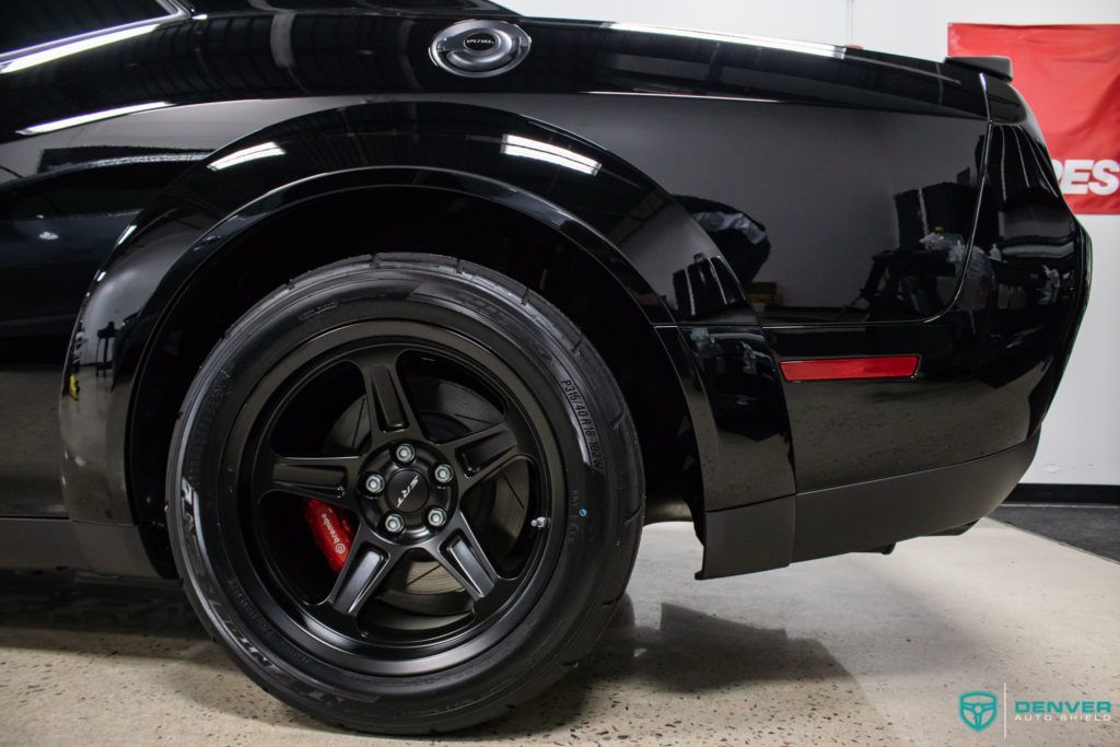 A black dodge challenger is parked in a garage.