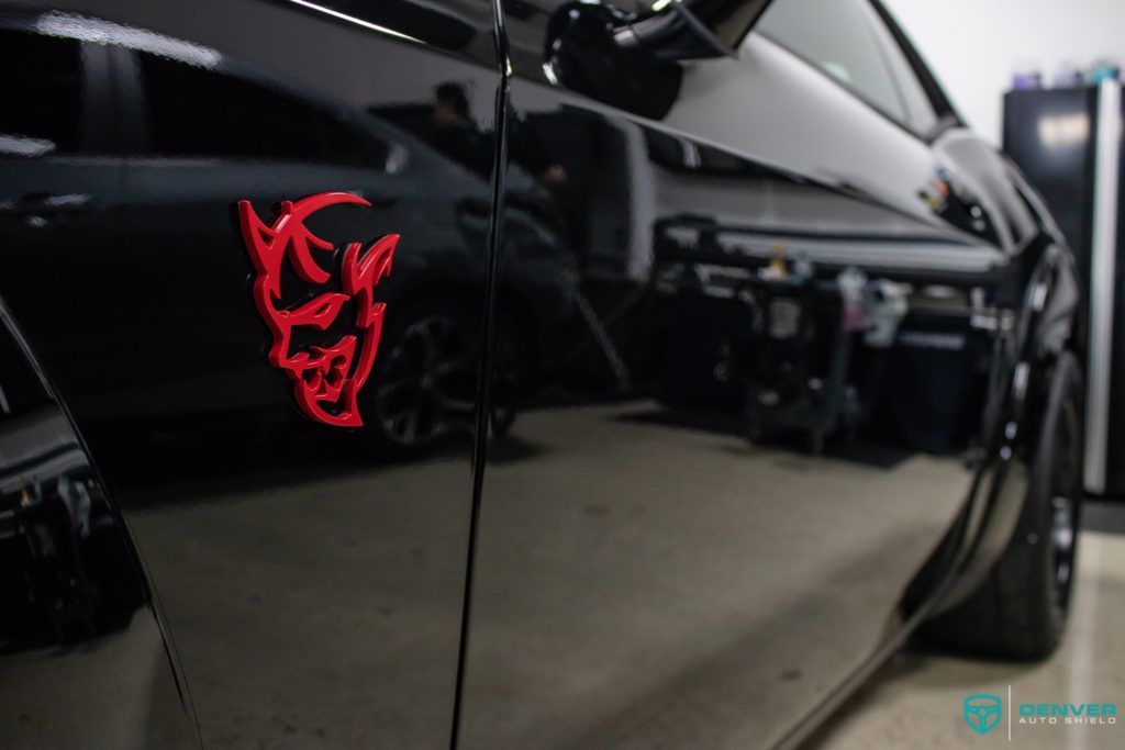 A black car with a red demon head on the side of it