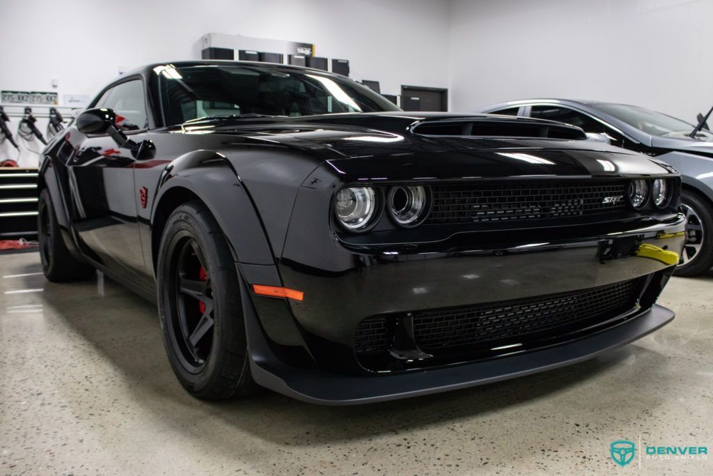 A black dodge challenger demon is parked in a garage.