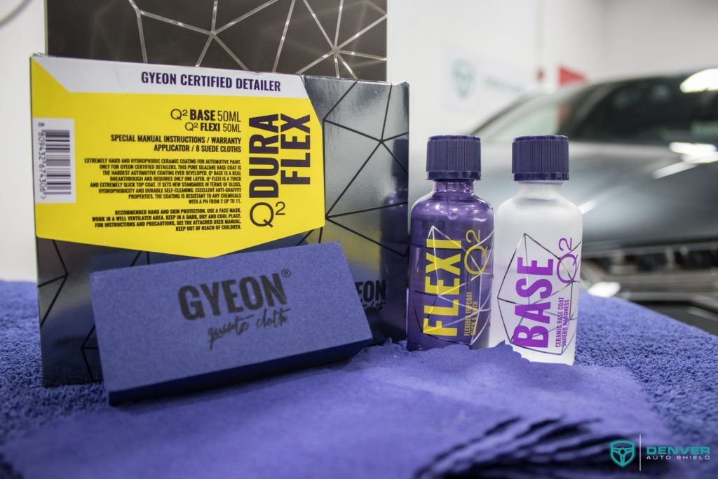 A bottle of gyeon dura flex sits on a towel next to a car