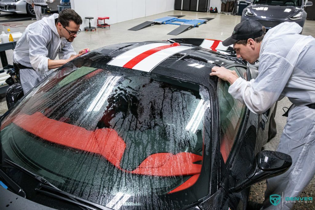 Two men are working on a car in a garage.