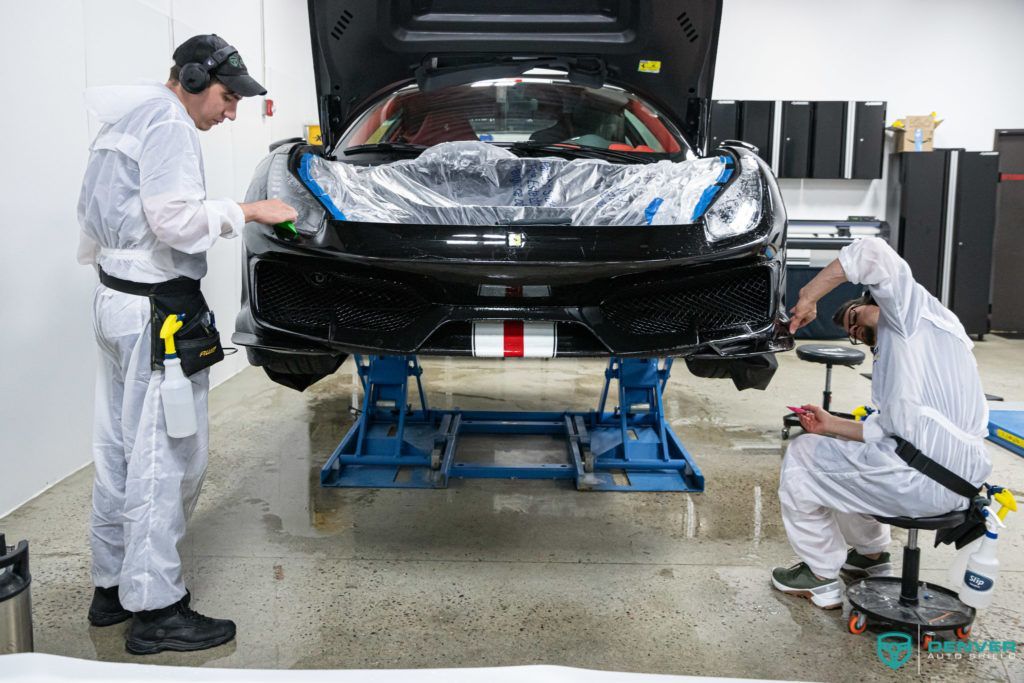 Two men are working on a car in a garage.