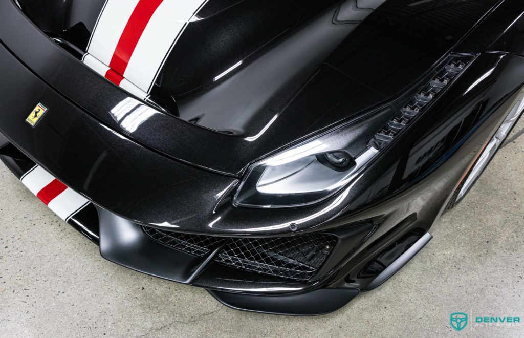 A black ferrari with red and white stripes on the hood