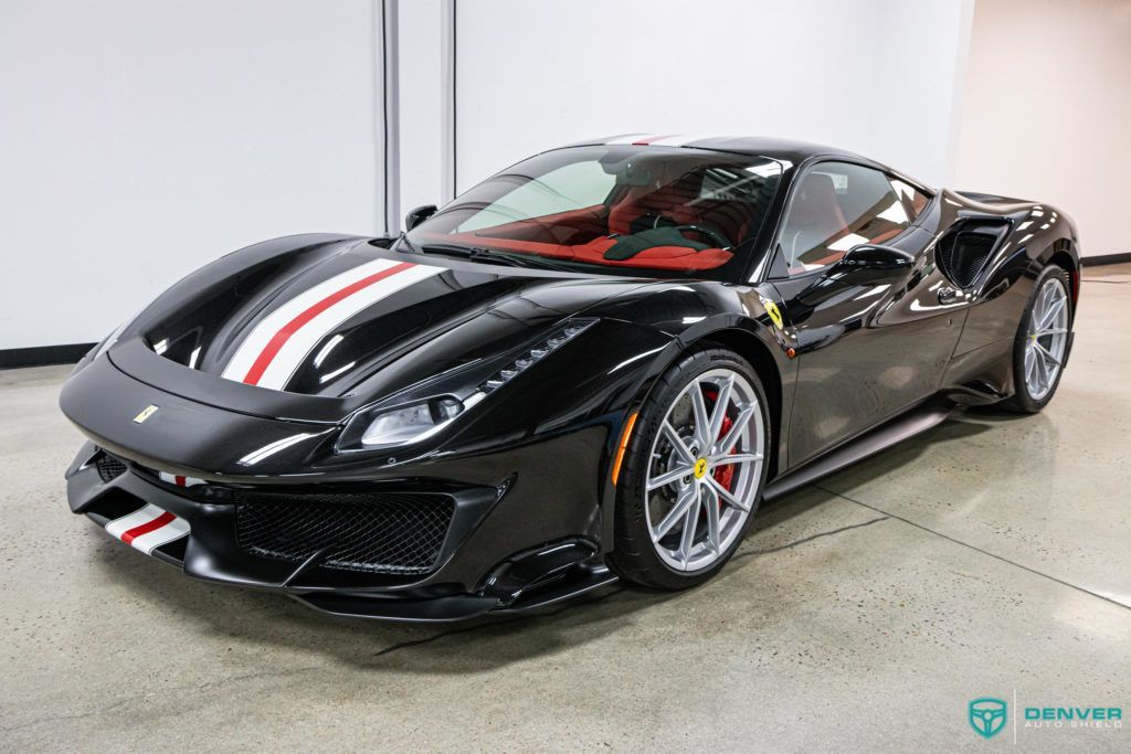 A black ferrari 488 pista is parked in a garage.