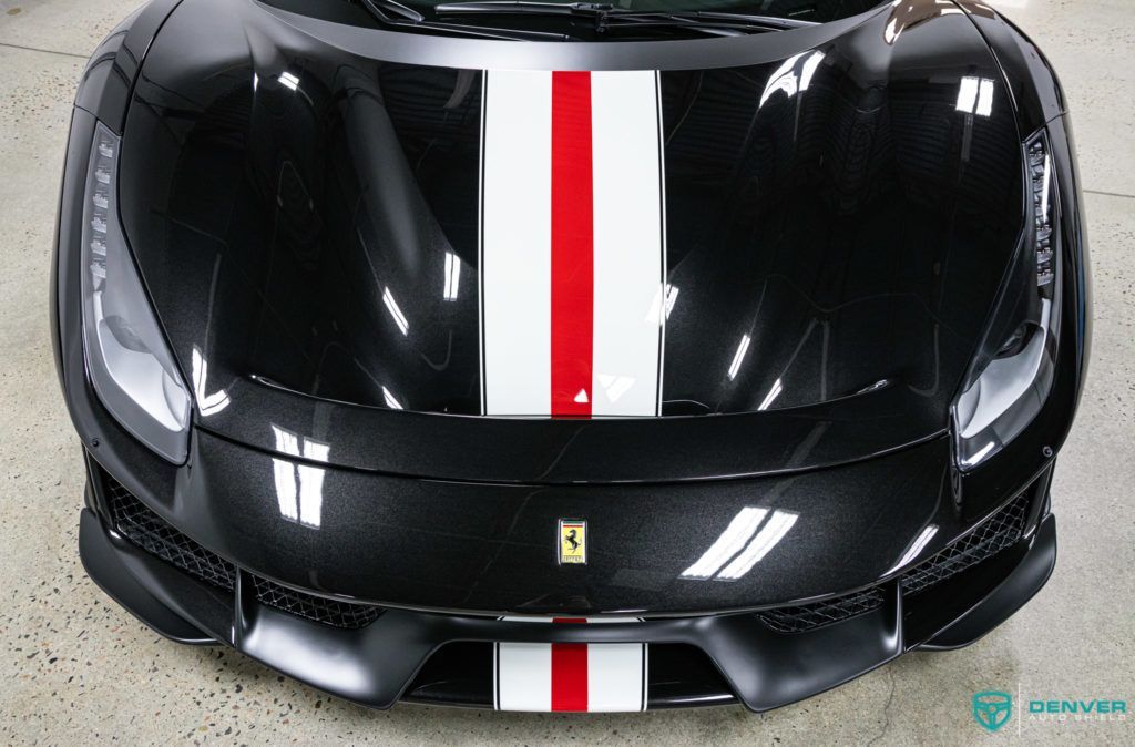 A black sports car with a red and white stripe on the hood