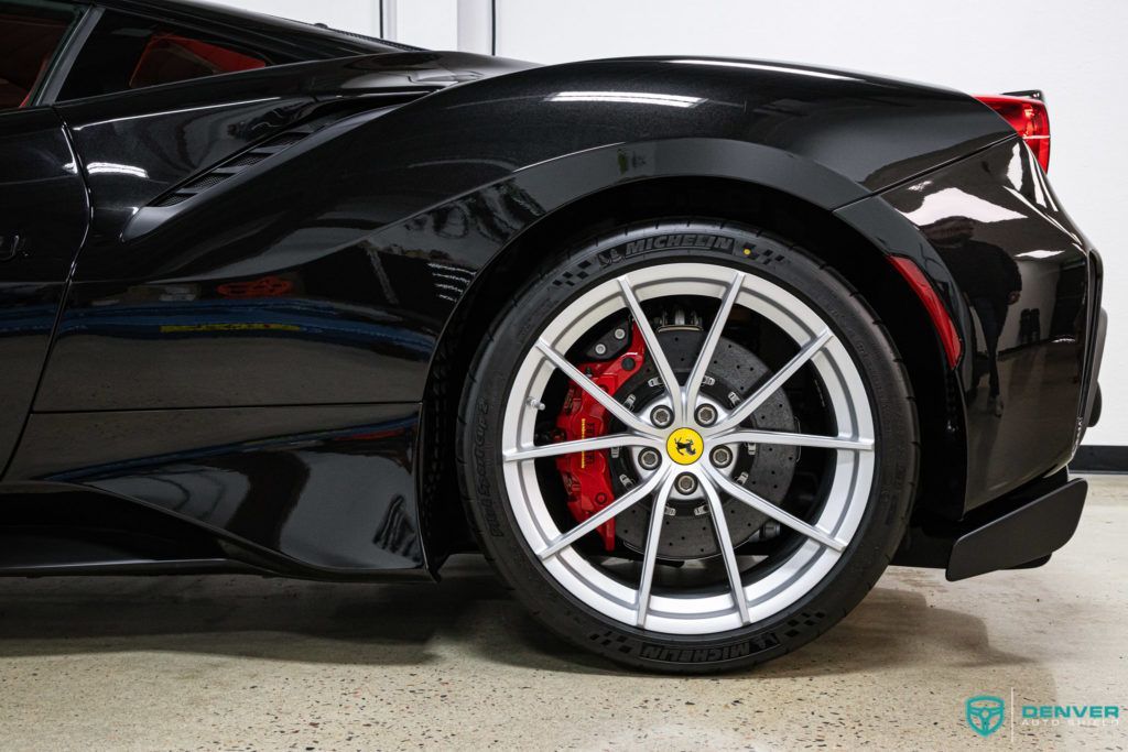 A black ferrari 488 gtb is parked in a garage.