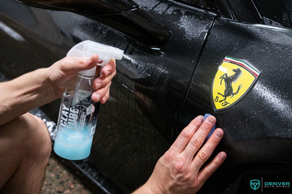 A person is cleaning a ferrari with a spray bottle.