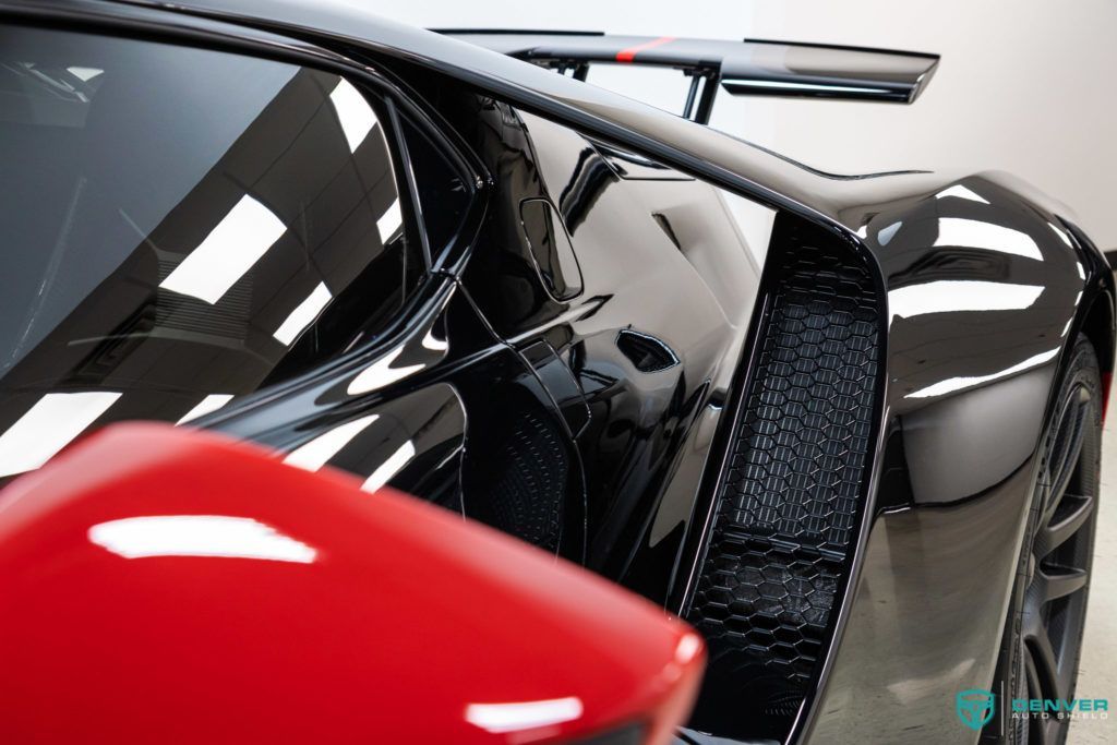 A black sports car is parked next to a red car