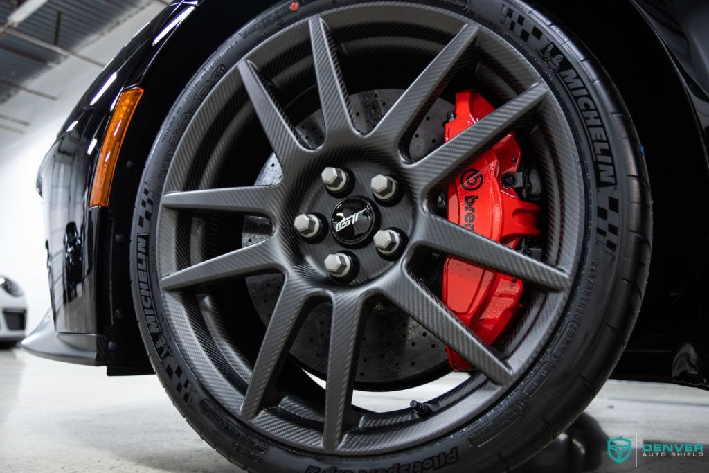 A close up of a car wheel with a red brake caliper