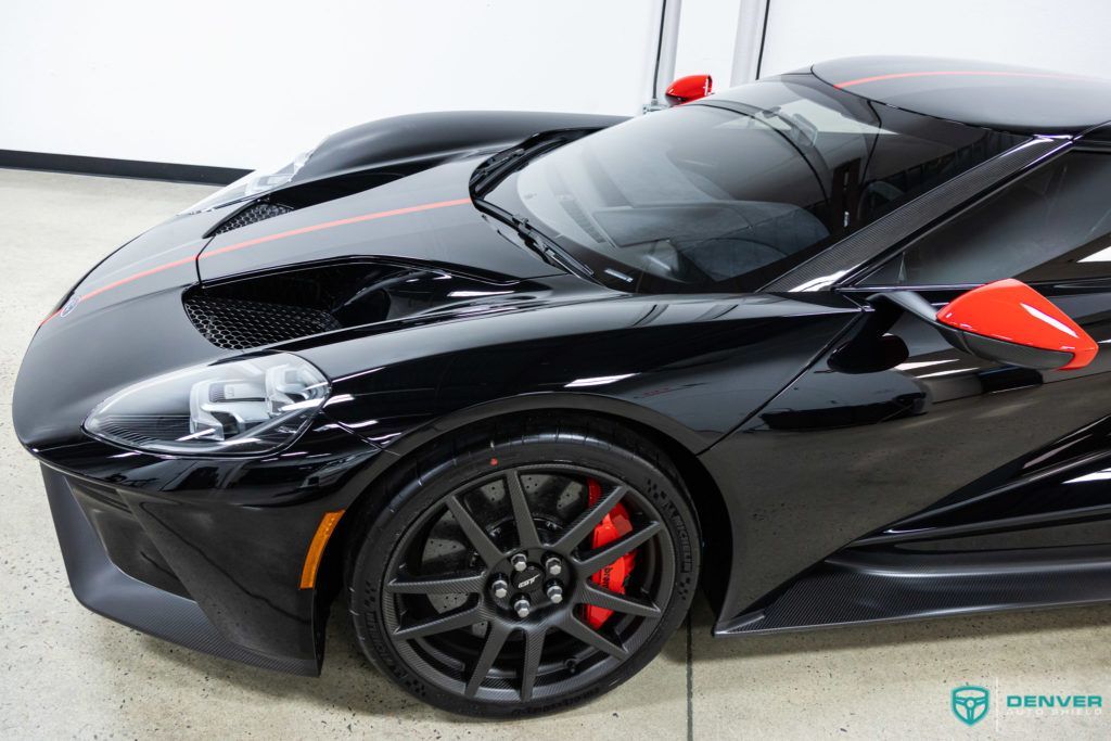 A black sports car with the hood up is parked in a garage.