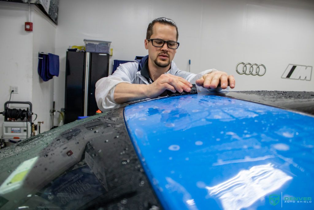 A man is working on a blue car in a garage.