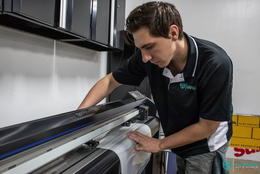 A man is working on a large printer in a room.