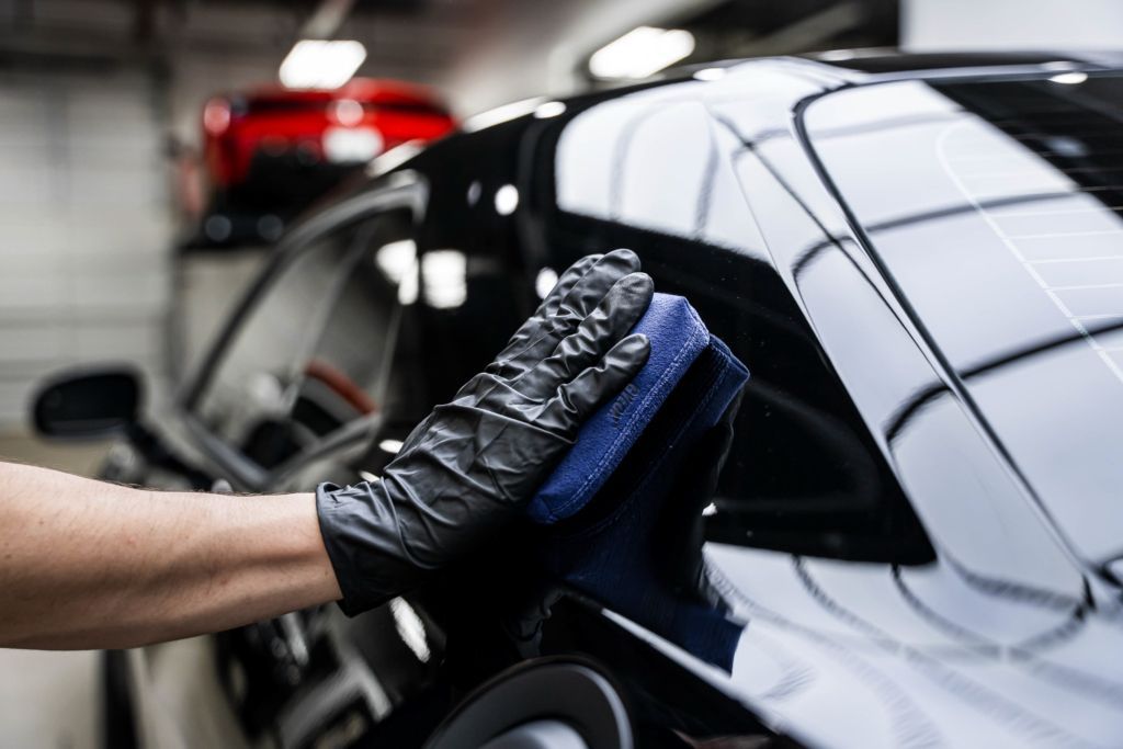 A person is polishing a car with a sponge.