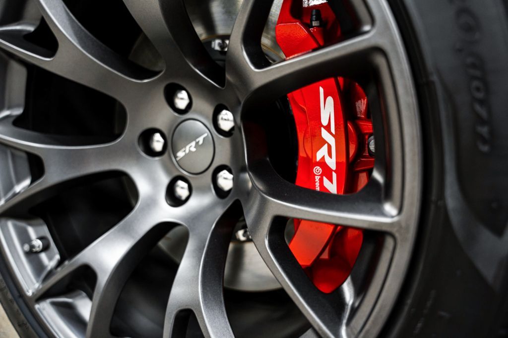 A close up of a car wheel with a red brake caliper that says srt