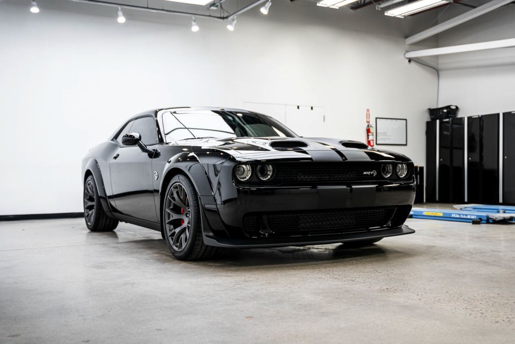 A black dodge challenger is parked in a garage.