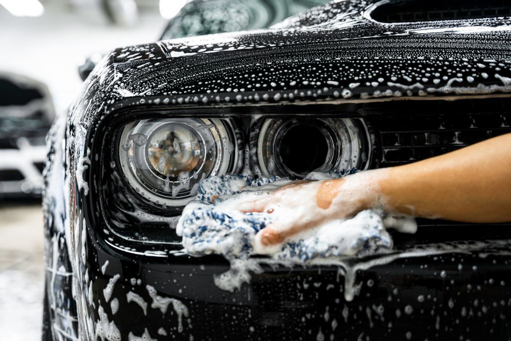 A person is washing a car with soap and a towel.