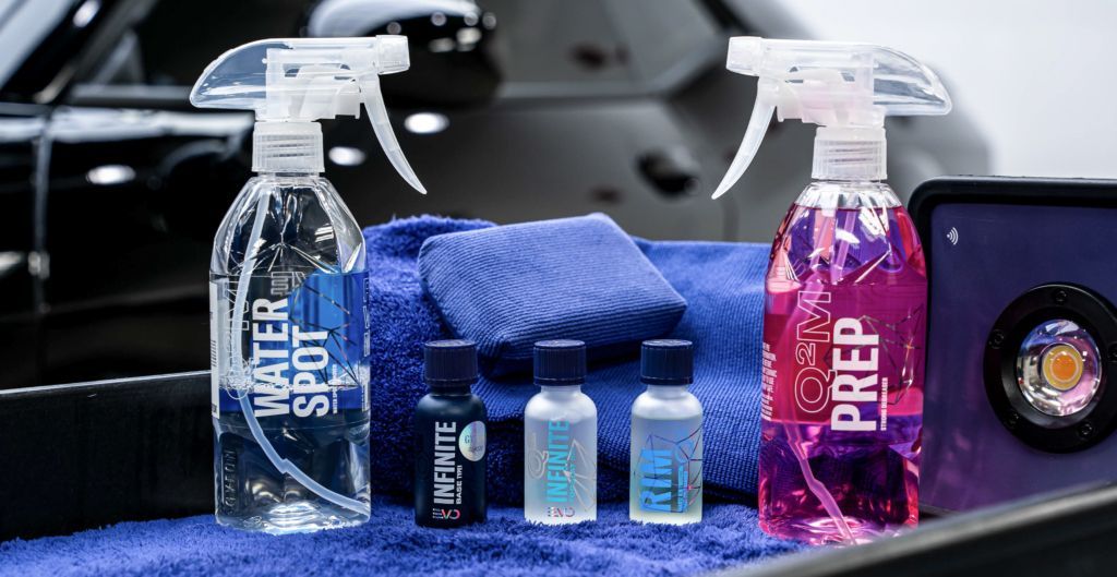 A couple of spray bottles sitting on top of a blue towel next to a car.