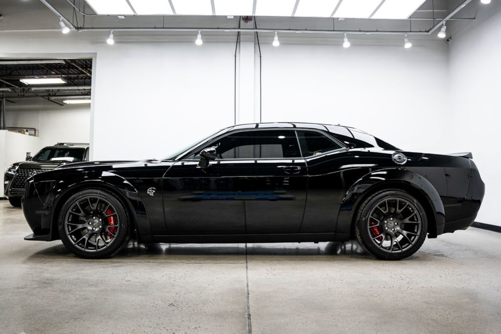 A black dodge challenger is parked in a garage.