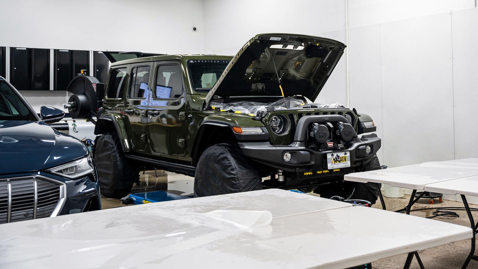 A jeep is parked in a garage with its hood open.