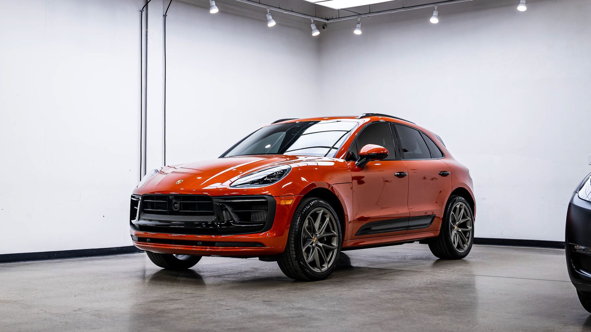 A red porsche macan turbo is parked in a garage.