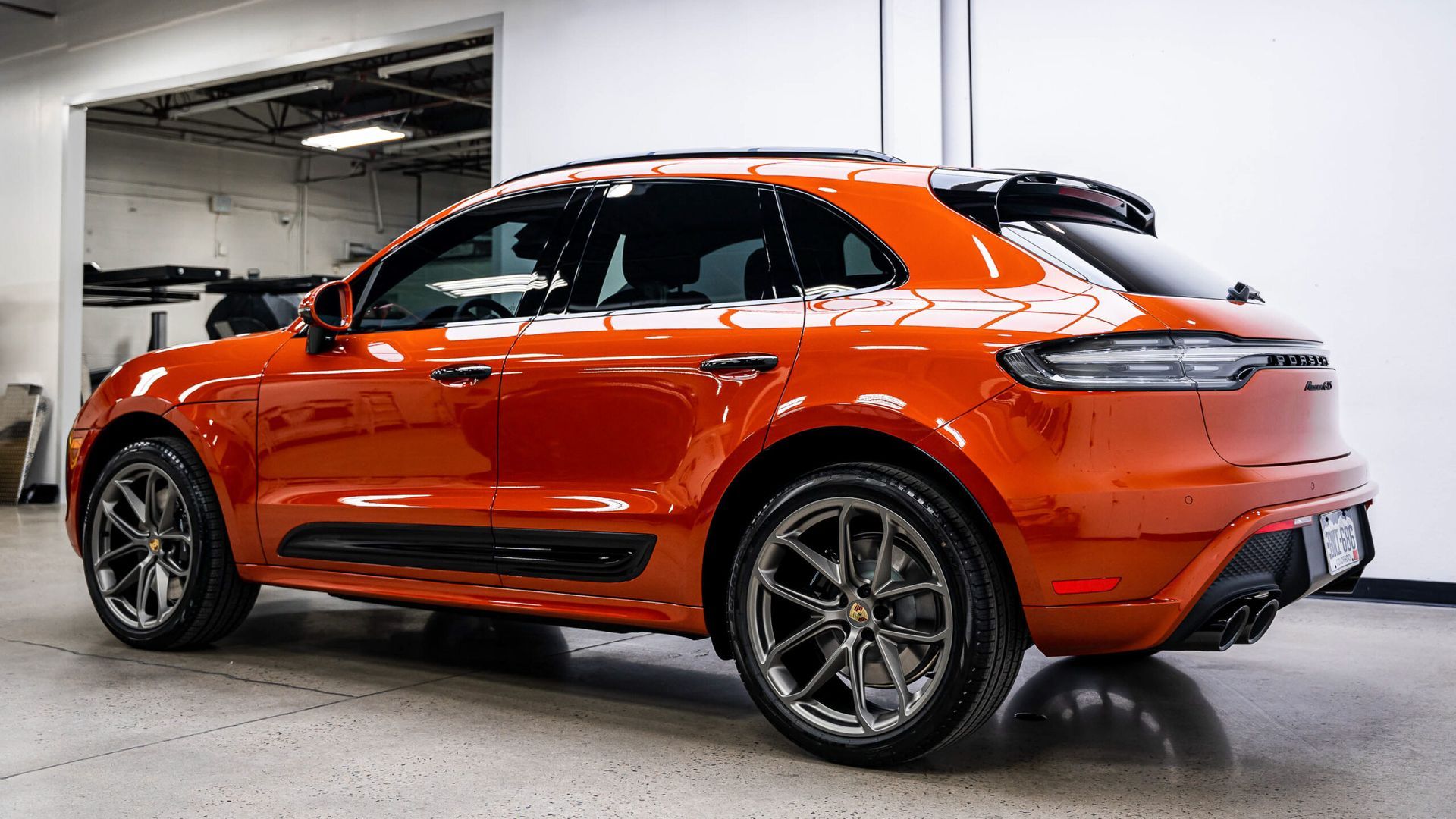 A red porsche macan is parked in a garage.