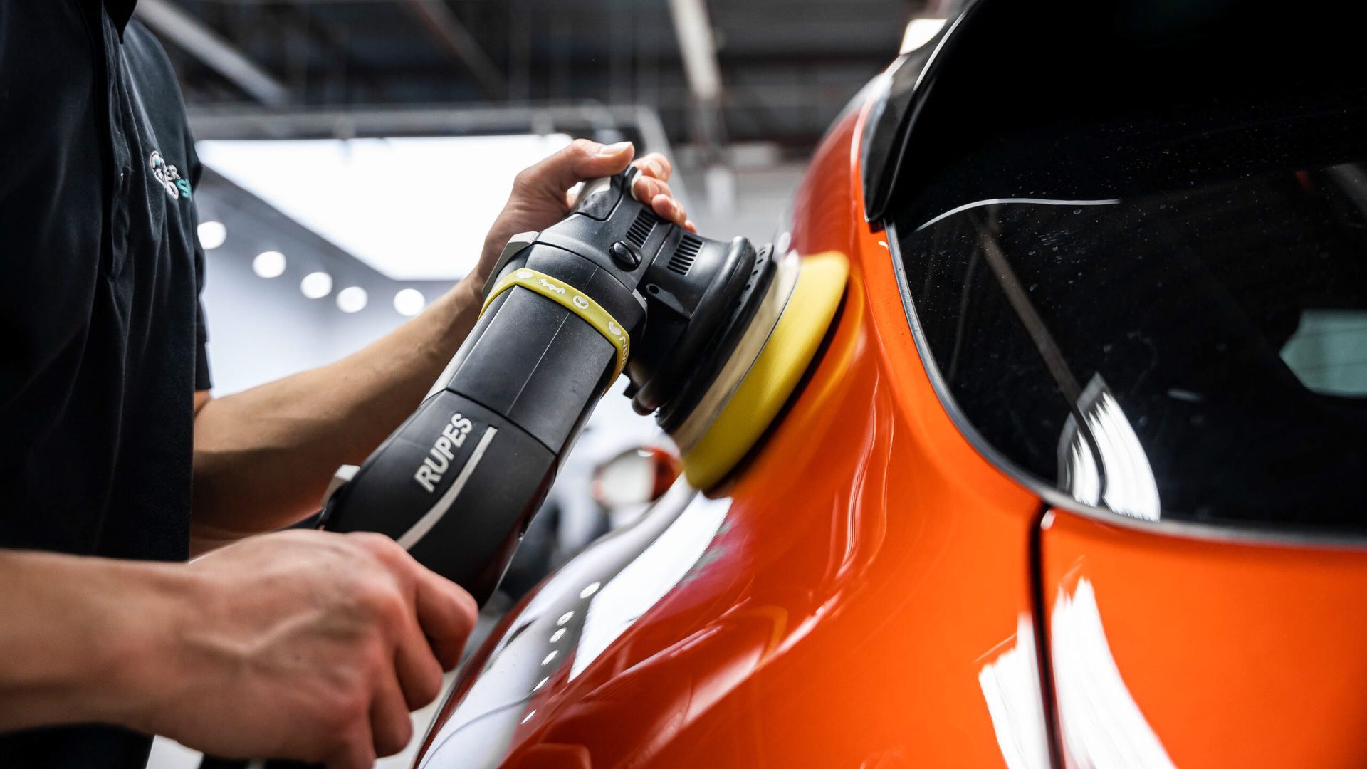 A man is polishing a car with a machine.