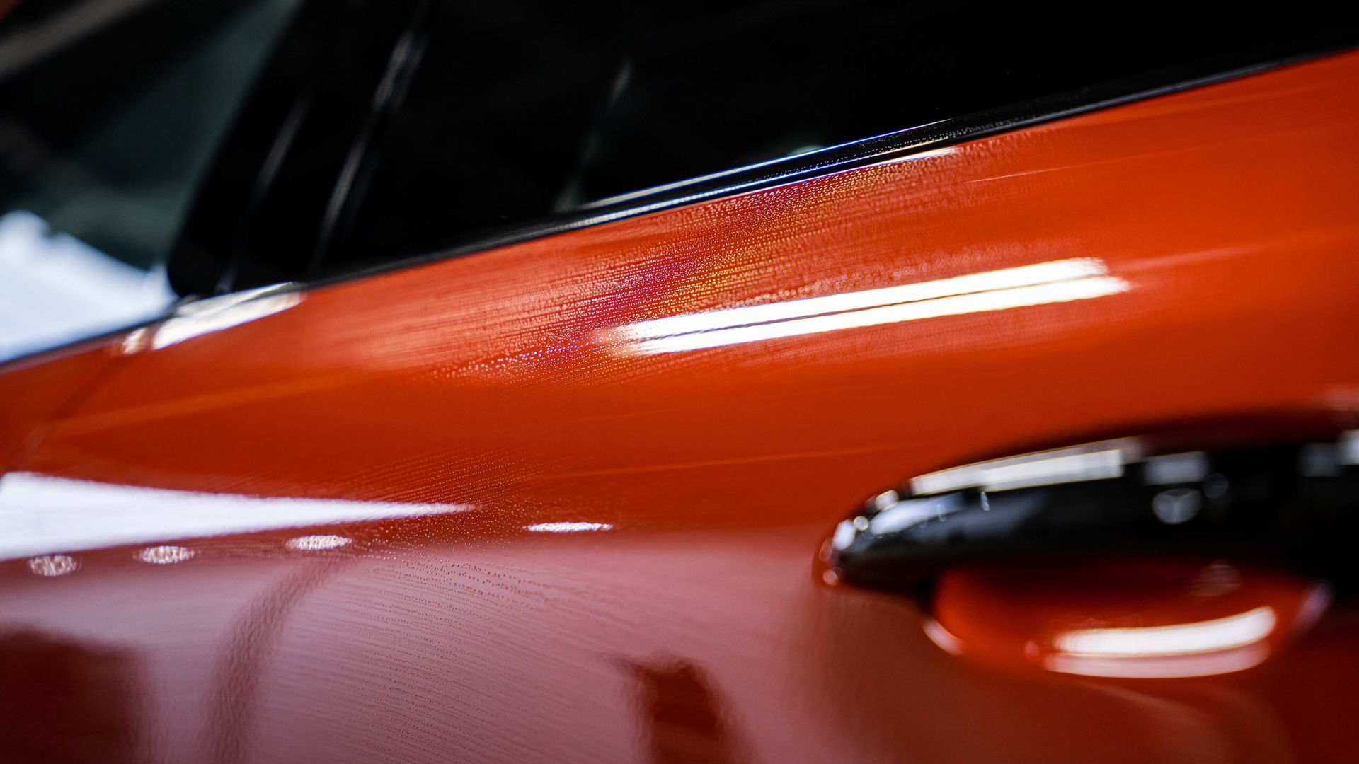 A close up of the door handle of a red car.