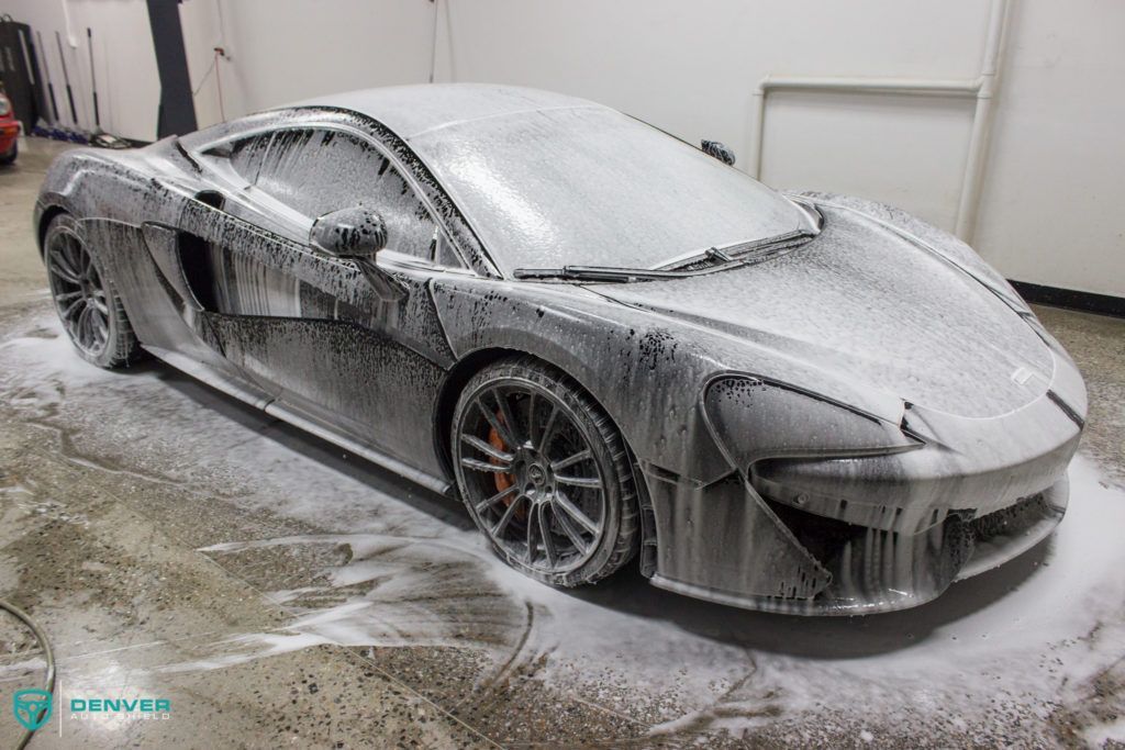 A car is covered in foam in a garage.