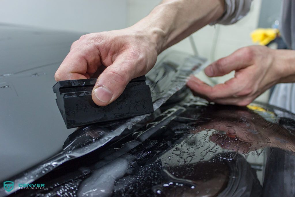 A person is cleaning a car with a sponge.