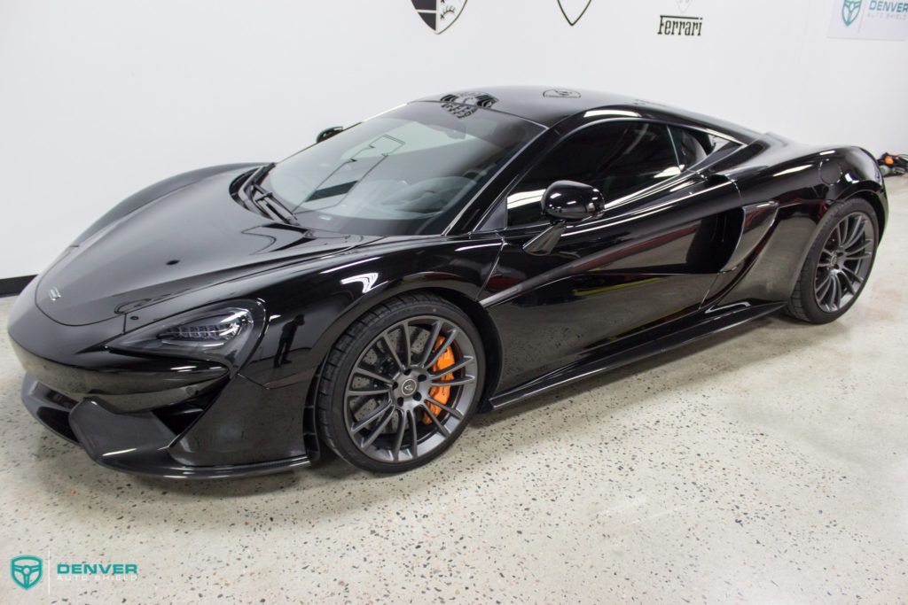 A black sports car is parked in a garage.