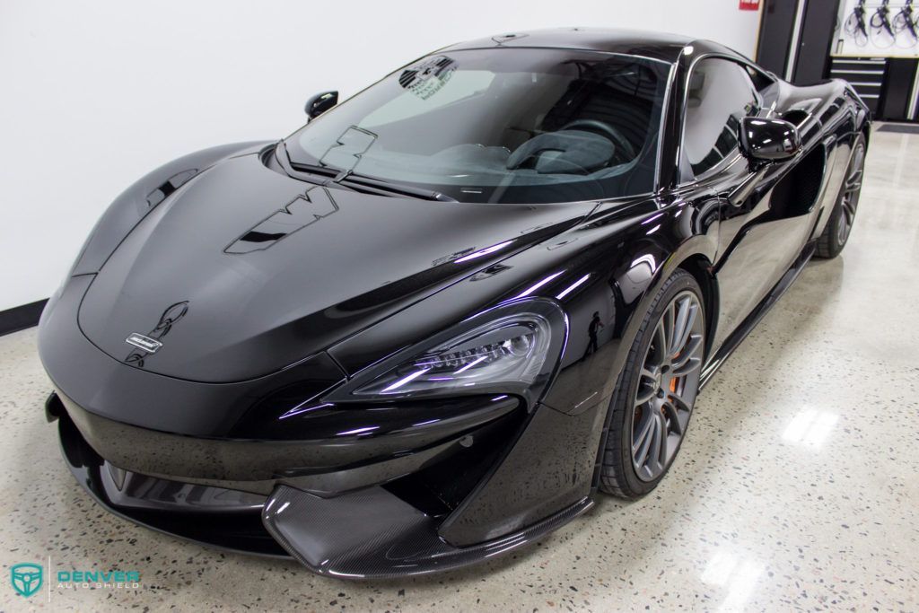 A black sports car is parked in a garage.