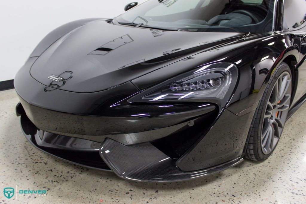 A black sports car is parked in a garage.