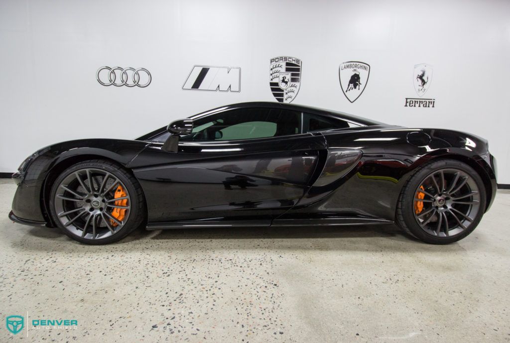 A black sports car is parked in a garage.