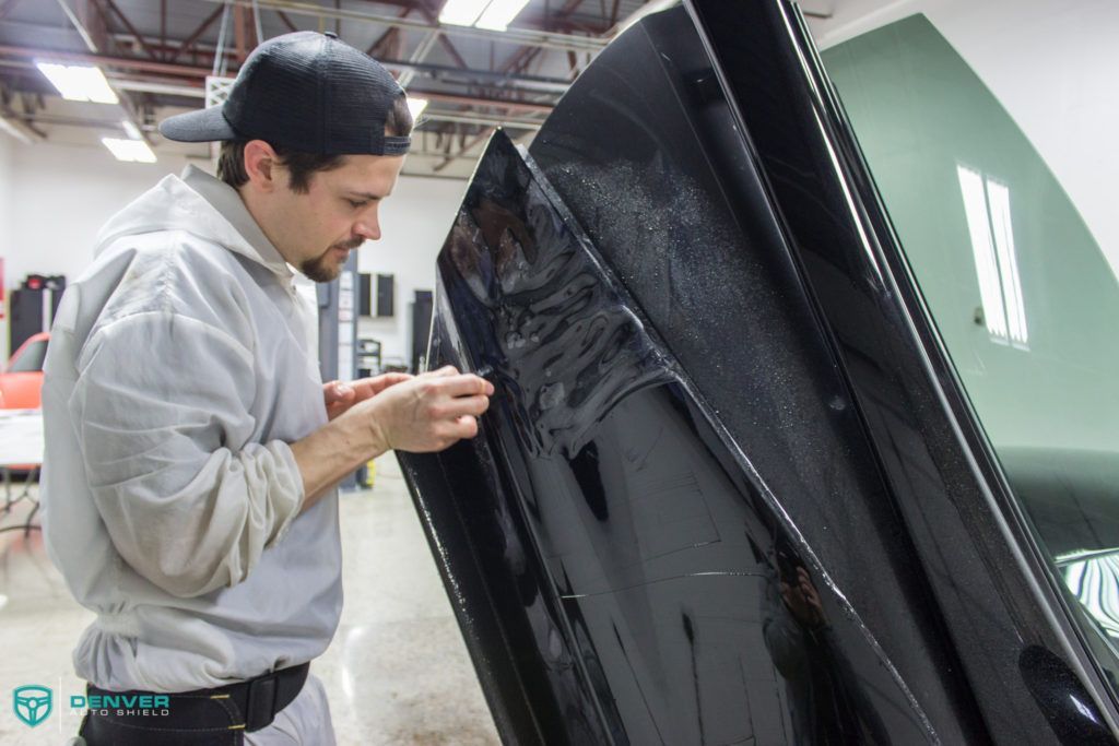 A man is working on a black car in a garage.