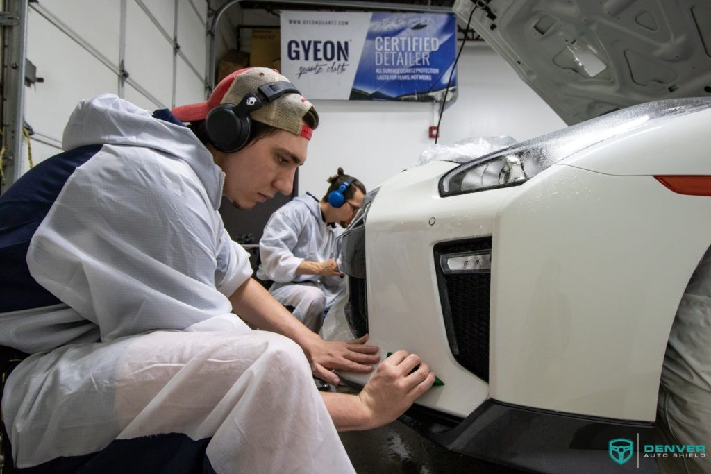 Two men are working on a white car in a garage.