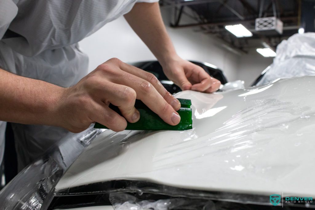 A person is wrapping a car with plastic wrap.