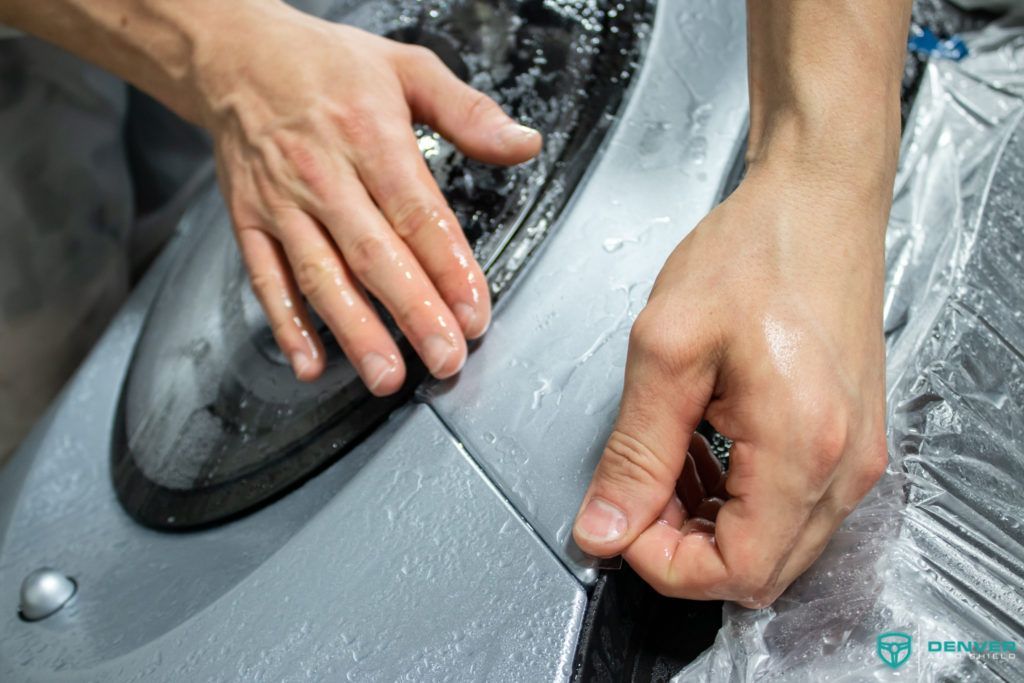 A person is wrapping a car with plastic wrap.