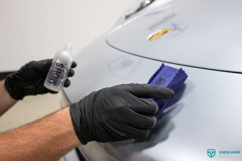 A person wearing black gloves is applying ceramic coating to a car.