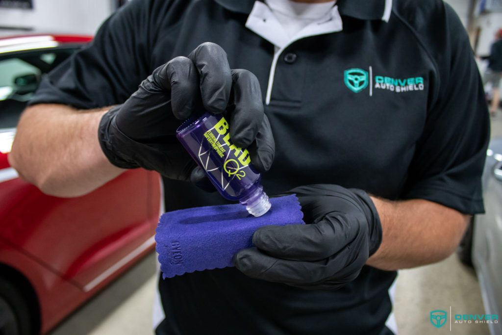 A man wearing black gloves is holding a bottle of polish on a sponge.