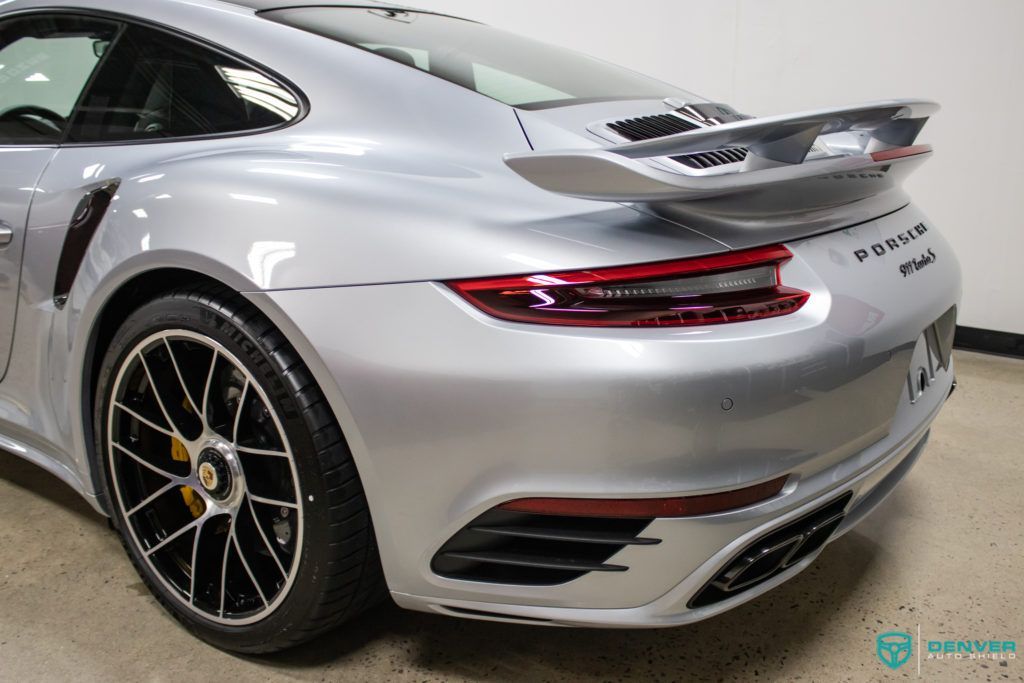 The rear end of a silver porsche turbo is shown