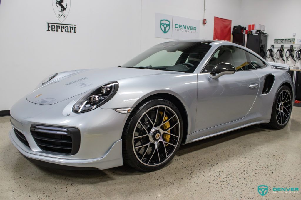 A silver porsche 911 turbo s is parked in a garage.